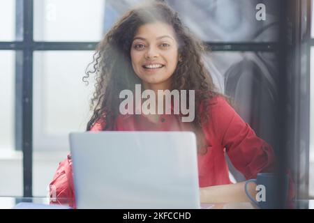 Porträt einer jungen erfolgreichen kaukasischen Geschäftsfrau, die am Schreibtisch sitzt und am Laptop-Computer im Stadtbüro arbeitet Stockfoto