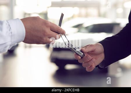 Der Autoverkäufer gibt die Schlüssel den Kunden, die den Kaufvertrag unterzeichnet haben Stockfoto