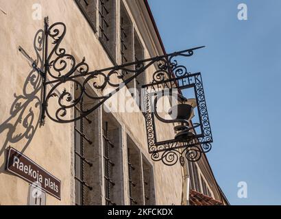 Estland, Tallinn - 21. Juli 2022: Nahaufnahme eines bräunlich kunstvoll geschmiedeten Metallteils als Apothekenschild, das vor einer beigen Wand am Rathausplatz hängt Stockfoto