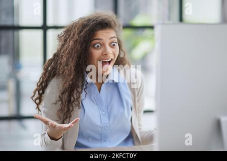 Expressive junge Frau offen Mund Überprüfung Rabatte für Online-Shopping sitzen am Desktop . Stockfoto