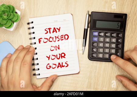 Inspirierendes Zitat – Bleib auf deine Ziele konzentriert. Mit einer Textnachricht auf einem rosa Aufkleber auf einem grünen Notizblock. Stockfoto