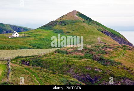 Blick auf Foel-y-Mwnt und die Holy Cross Church vom Cardigan Coastal Path in Ceredigion Wales Stockfoto