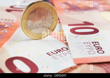 Aufrechte eine-Euro-Münze auf zehn Euro-Banknoten in Papierwährung. Stockfoto