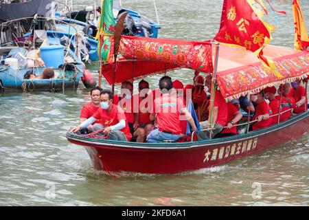 Eine Gruppe von Menschen, die mit einem roten Boot beim Drachenbootfest in Taio O, Hongkong, unterwegs sind Stockfoto