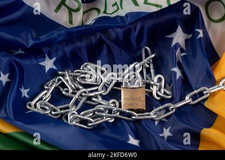 Kette, Vorhängeschloss und brasilianische Flagge symbolisieren die Sklaverei im Land Stockfoto