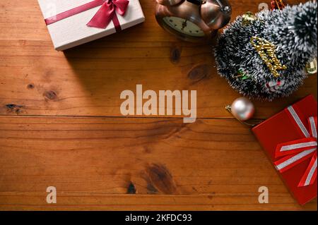 Top shot, Holztischplatte mit Geschenkboxen, kleinem Weihnachtsbaum, Vintage-Wecker und Kopierplatz für die Anzeige Ihres Textes. Stockfoto