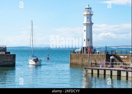 Edinburgh, Schottland-Juli 31 2022:an einem heißen, sonnigen Tag treibt ein Ausflugsboot am Newhaven Lighthouse vorbei, auf glattem, blauem Meer, Richtung Firth of Forth Stockfoto