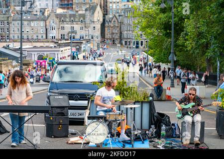 Edinburgh, Schottland-Juli 30 2022:The Dark Witze Gruppe,spielen in der Mitte der Hauptstraße runnin vorbei am Bahnhof,vorübergehend geschlossen während der Fr. Stockfoto