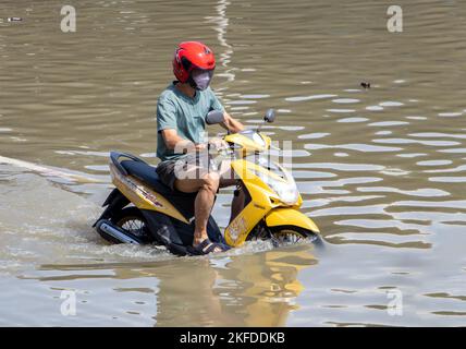 SAMUT PRAKAN, THAILAND, OCT 29 2022, Ein Motorradfahrer fährt durch eine überflutete Straße Stockfoto