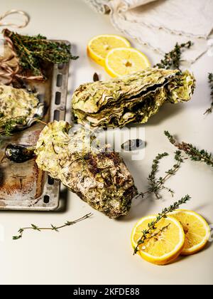 Riesige frische pazifische Austern auf hellem Hintergrund. Zitrone und Orangano. Selektiver Fokus. Vertikale Aufnahme Stockfoto