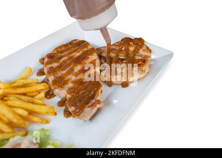 Stempelschnitt von Schweinefleisch Steak mit französisch in weißen Teller auf weiß isoliert gebraten. Stockfoto