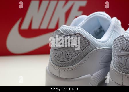 Eine Nahaufnahme von dreifach weißen Nike Air Max 90 Sneakern. Die Fersenlasche mit dem Markennamen und dem Logo. Stockfoto