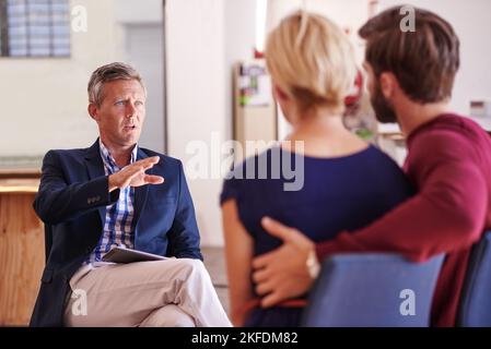 Sie in die richtige Richtung lenken. Junges Paar diskutiert Investitionspläne mit einem Finanzberater. Stockfoto