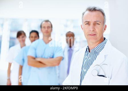 Arzt mit medizinischem Personal. Konzentrieren Sie sich auf den Arzt mit seinem Team im Hintergrund. Stockfoto