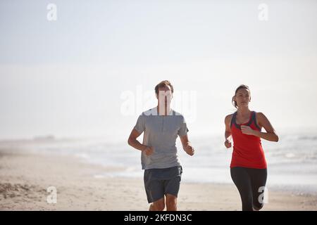 Joggen am frühen Morgen am Strand. Ein junges Paar trainiert im Freien. Stockfoto