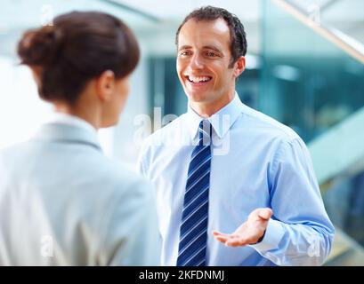 Lächelnder Geschäftsmann, der mit seinem Kollegen diskutiert. Porträt eines lächelnden Geschäftsmanns, der mit seinem Kollegen diskutiert. Stockfoto