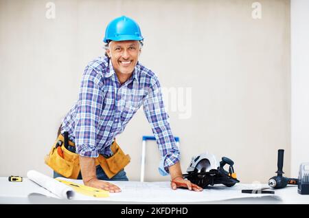 Ausgereifter Ingenieur, der die Blaupause prüft. Porträt eines lächelnden, reifen Ingenieurs, der die Blaupause überprüft. Stockfoto
