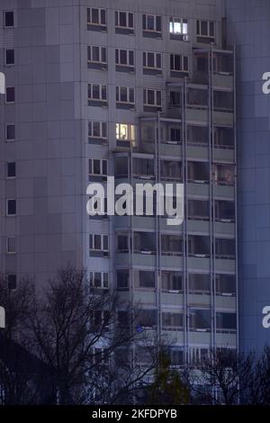 18. November 2022, Sachsen-Anhalt, Magdeburg: Die ersten Lichter brennen in den Fenstern eines Hochhauses in der Hauptstadt Sachsen-Anhalt. Um Verzögerungen bei der Übertragung von Wohnungszuschüssen zu vermeiden, plädiert der Hauptgeschäftsführer des Deutschen Städtebundes Anfang des Jahres für eine unkomplizierte Vorauszahlung. Normalerweise benötigen die Ämter fünf bis sieben Monate, um die Anträge zu bearbeiten, aber aufgrund der Multiplikation der Anträge wird dies jetzt noch länger dauern. Aufgrund der hohen Energiepreise sind die Menschen jedoch auf den Wohnraum angewiesen Stockfoto