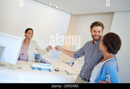 Ein junges Paar, das in ein Hotel eincheckt, wird sich auf das Zimmer begeben. Stockfoto