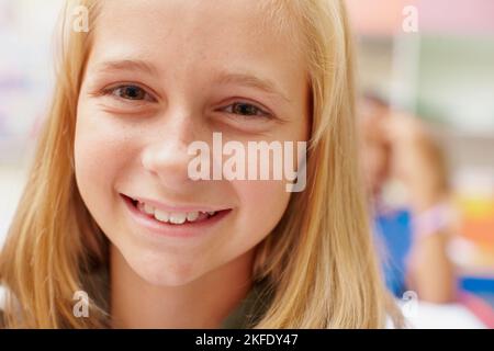 Jeden Tag lieben, Neues lernen. Nahaufnahme eines niedlichen jungen Grundschulmädchen, das an der Kamera lächelt - Copyspace. Stockfoto