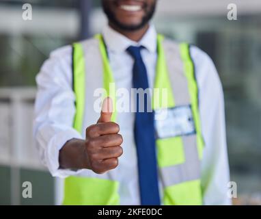 Schwarzer Mann, Bauarbeiter oder Daumen nach oben Erfolg, Unterstützung und Vertrauen in Bürogebäude, Baustelle oder Industrielager. Zoom, Lächeln oder Stockfoto