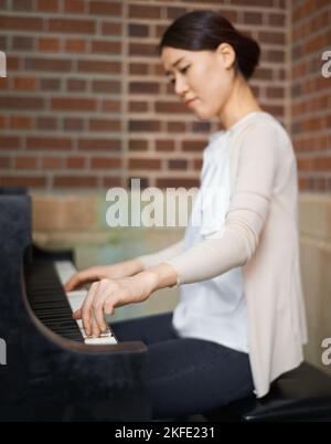 Lassen Sie sich von der Musik bewegen. Eine junge Frau, die elegant in ihrem Zuhause gekleidet ist. Stockfoto