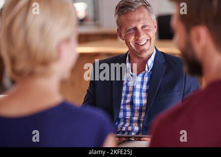 Sie beide können sehr stolz auf Ihre finanziellen Entscheidungen sein. Junges Paar diskutiert Investitionspläne mit einem Finanzberater. Stockfoto