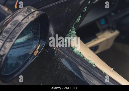 Nahaufnahme des Seitenspiegels eines schwarzen Autos und zertrümmerte Glasscheibe. Unfall- und Fahrzeugcrash-Konzept. Linkes Fenster. Hochwertige Fotos Stockfoto