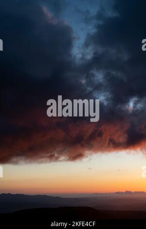 Dramatischer Sonnenuntergang Himmel mit orangen und schwarzen Wolken und ein Flugzeug fliegen, vertikale Aufnahme Stockfoto