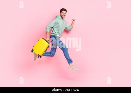 In voller Länge Profil Seite Foto von fröhlich positive Junge gehen bewegen leeren Raum Eile Registrierung fliegen im Ausland isoliert auf rosa Hintergrund Stockfoto