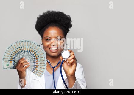 Schöne afroamerikanische Ärztin hält Fan von Geld hundert Dollar-Scheine Stockfoto