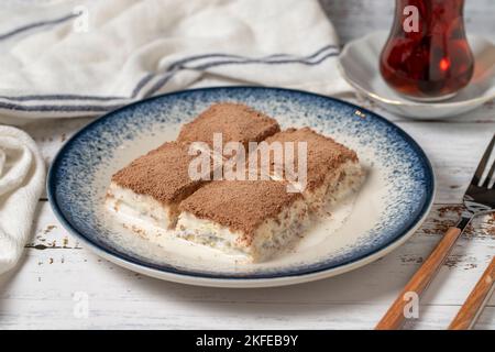 Kaltes Baklava auf weißem Holzhintergrund. Baklava mit Milch und Pistazie. Köstlichkeiten der mediterranen Küche. Nahaufnahme Stockfoto