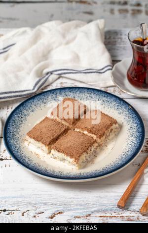 Kaltes Baklava auf weißem Holzhintergrund. Baklava mit Milch und Pistazie. Köstlichkeiten der mediterranen Küche. Nahaufnahme Stockfoto