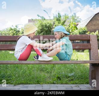 Zwei Kinder im Vorschulalter, Mädchen und Jungen, sitzen auf einer gegenüberliegenden Bank. Die Liebe der Kinder, Freundschaft, zärtliche Gefühle, Fürsorge zwischen Bruder und Stockfoto