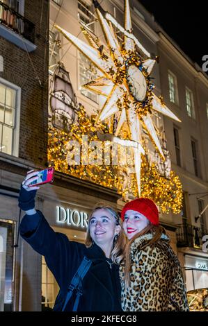 London, Großbritannien. 17.. November 2022. Ein Selfie vor dem Dior Store - über der Bond Street und an den Ladenfronten vieler der dort ansässigen Luxuswarenhändler leuchten Weihnachtslichter. Kredit: Guy Bell/Alamy Live Nachrichten Stockfoto