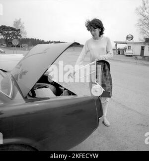 Einkaufen in der 1960s. Eine Dame hat ihr Auto im Supermarkt geparkt und nimmt ihren Warenkorb auf dem Parkplatz heraus. Ein Neuheitsartikel, der ursprünglich aus den USA kam. Schweden april 14 1966 Conard Ref. 5236 Stockfoto