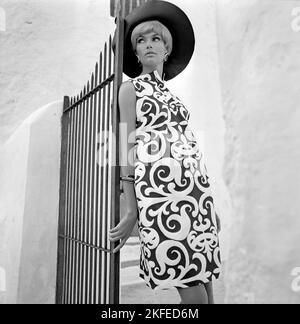 Fashion Shooting auf der spanischen Insel Ibiza im Jahr 1960s. Ein Modelmodell vor Ort modelliert das typische Sommerkleid und den Hut. 1967 Stockfoto