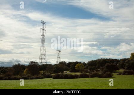 Elektrischer Hochspannungsturm entlang des Feldes, bis seine Kabel die Stadt erreichen, wo sie ihre Energie transportiert Stockfoto