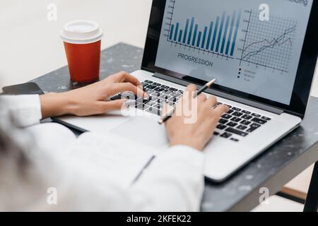 Junge Frau, die Finanzdaten überprüft, sitzt an einem Tisch in einem Café. Stockfoto