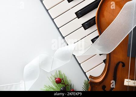 Detail der musikalischen Veranstaltung weihnachten Konzept Hintergrund mit Klavier und Violine auf weißem Tisch. Draufsicht. Stockfoto