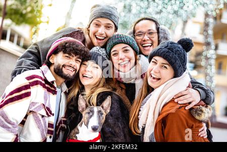 Fröhliche multikulturelle Jungs und Mädchen, die Selfie auf warmer Mode-Kleidung nehmen - trendiges Lifestyle-Konzept mit Millennial Freunde Gruppe, die Spaß zusammen haben Stockfoto