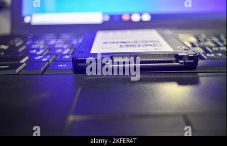 SSD-Laufwerke sind heutzutage sehr beliebt, SSDs werden auf Laptops platziert (dieses Foto sollte dunkel aussehen und blaues Licht verwenden). Stockfoto