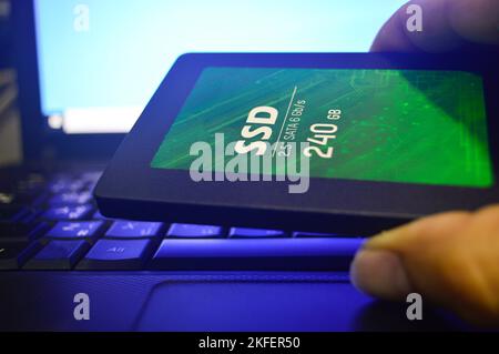 SSD-Laufwerke sind heutzutage sehr beliebt, SSDs werden auf Laptops platziert (dieses Foto sollte dunkel aussehen und blaues Licht verwenden). Stockfoto