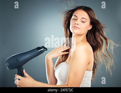 Haarpflege, Schönheit und Frau im Studio mit einem Haartrockner für Salon oder Friseur Mockup mit Kosmetik, Make-up und Wachstum Shampoo Produkt. Ästhetisch Stockfoto