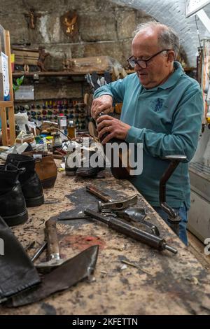 Kleine Schuhmacherwerkstatt. Handwerker wollen ein Paar handgefertigte Schuhe reparieren. Perugia, Umbrien, Italien, Europa Stockfoto