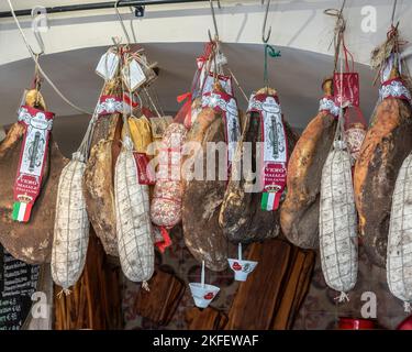 Geräuchertes Fleisch und Würstchen, die in einem Geschäft in Perugia zum Trocknen aufgehängt wurden. Perugia, Umbrien, Italien, Europa Stockfoto