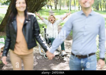 Glückliches Paar vergaß behinderte Frau im Rollstuhl im Freien. Stockfoto