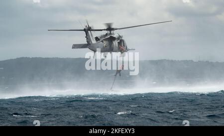 US Air Force-Paraskuemen, die dem Rettungsgeschwader 31. an Bord eines HH-60G Pave Hawk zugewiesen wurden, nachdem sie am 13. September 2022 ein Such- und Rettungstraining im Pazifischen Ozean absolviert hatten. Nach Erreichen des Extraktionspunktes wurden PJ's über einen Hebezeug aus dem Wasser zurück in das Flugzeug gehoben. Stockfoto