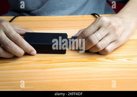 Mann, der ein schwarzes Netzteil anschließt Stockfoto