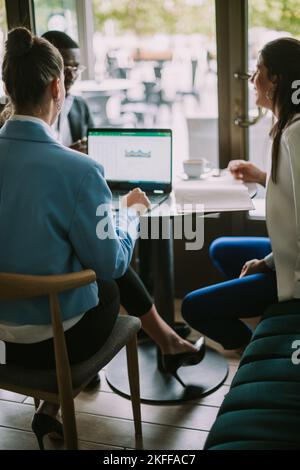 Drei Studenten sitzen und plaudern in einer Café-Bar über das neueste bevorstehende Projekt Stockfoto